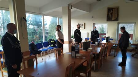 Pięć osób stojących przy stołach. Na stole sprzęt w pudłach.