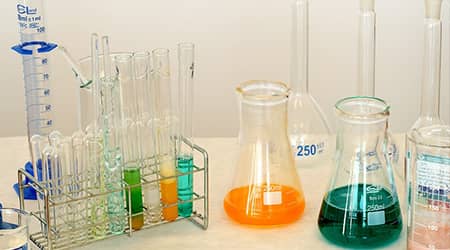 Zdjęcie przedstawiające różnej wielkości probówki i menzurki laboratoryjne.