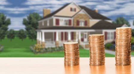 Zdjęcie monet ustawiony w trzy stosy. W tle widoczne budynki.