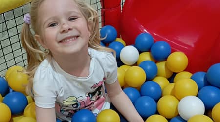 Uśmiechnięta dziewczynka w basenie wypełnionym plastikowymi kulkami 