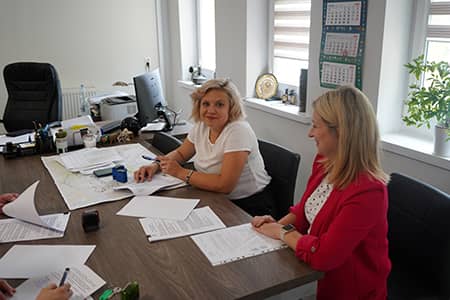 Dwie kobiety z dokumentami siedzące przy stole.