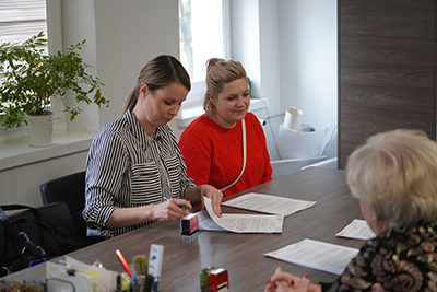 Trzy kobiety siedzące przy stole podczas podpisywania dokumentów.