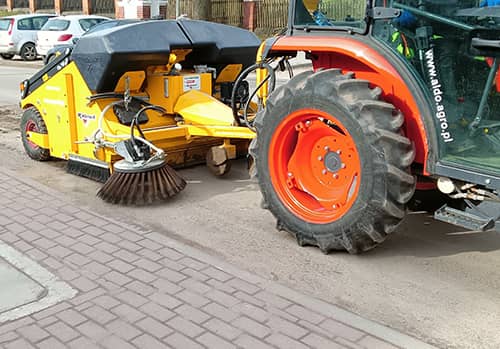 Zdjęcie traktora i zamiatarki podczas czyszczenia jezdni.