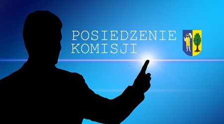 Grafika przedstawiająca postać wskazującą napis: posiedzenie komisji, w tle herb gminy.
